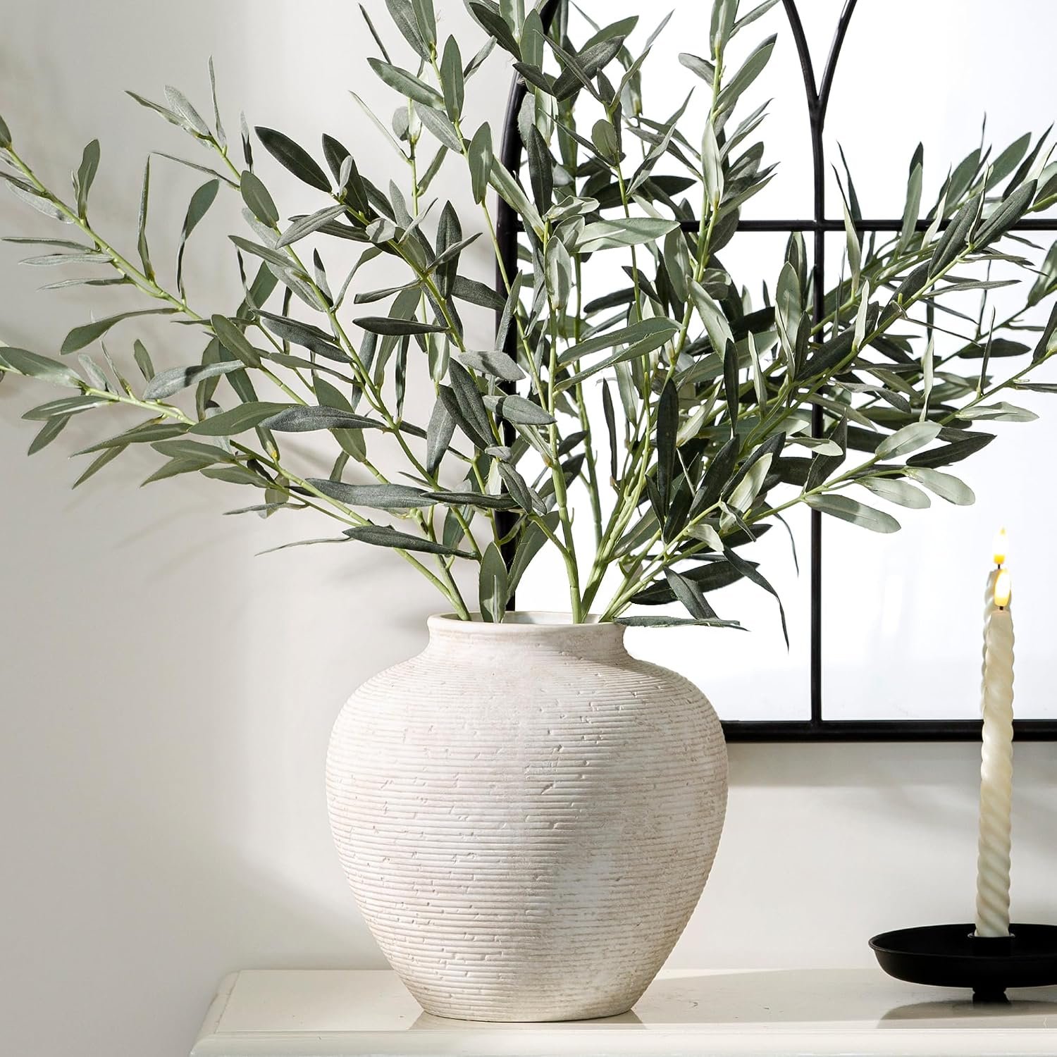 Large textured ceramic vase with green branches beside a taper candle, styled as a fall entryway console table focal point