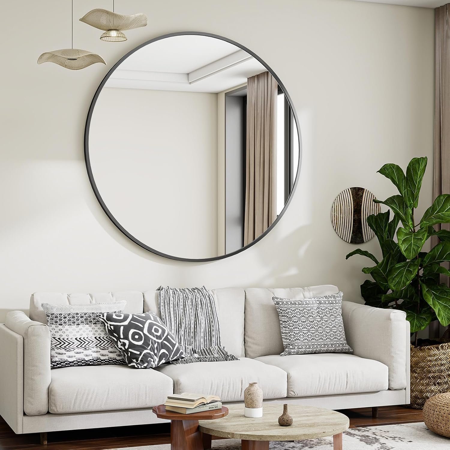 Large round black-frame mirror hung above a living room sofa with patterned pillows, a fiddle leaf fig, and a round coffee table